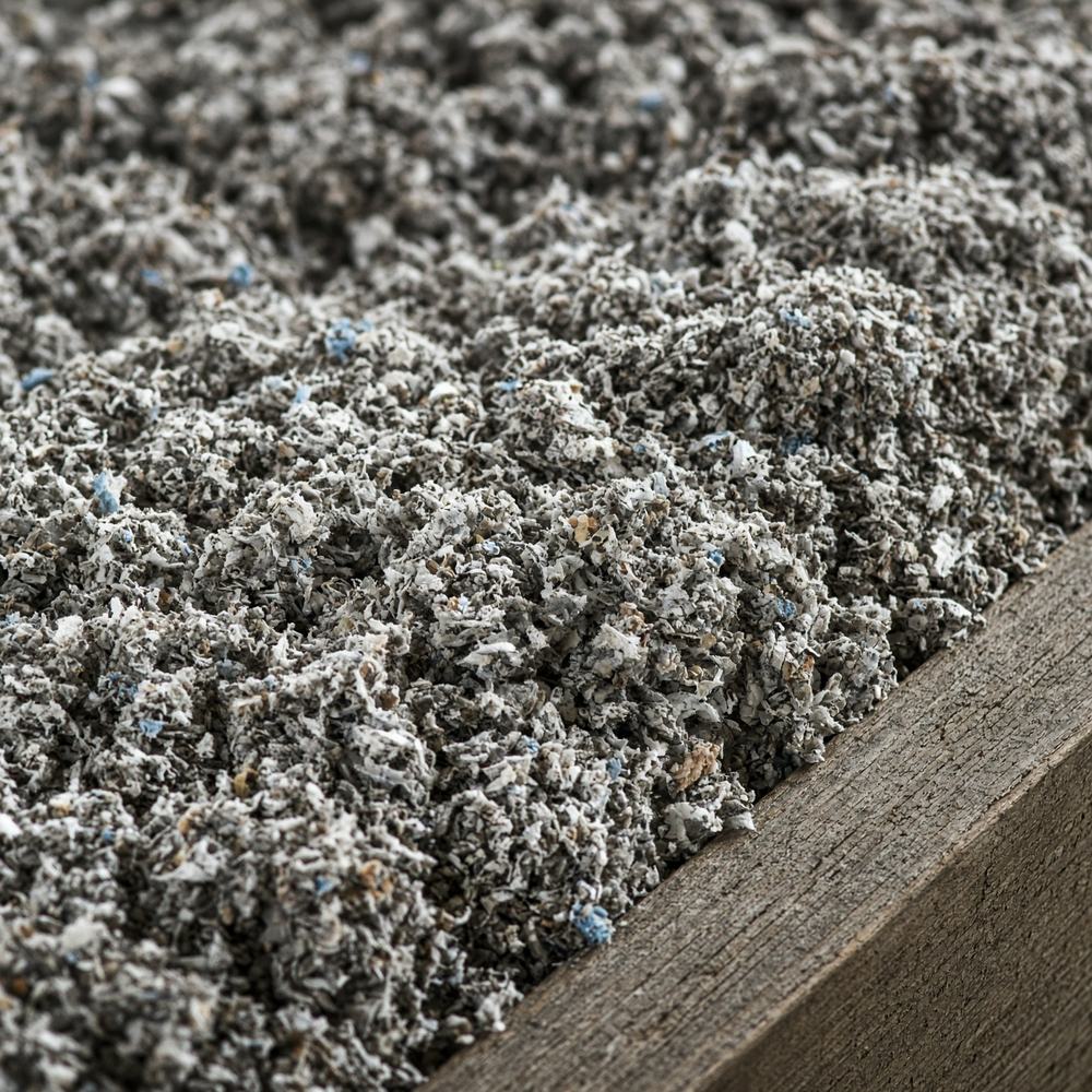 Close-up of gray cellulose loose-fill insulation against a wood joist